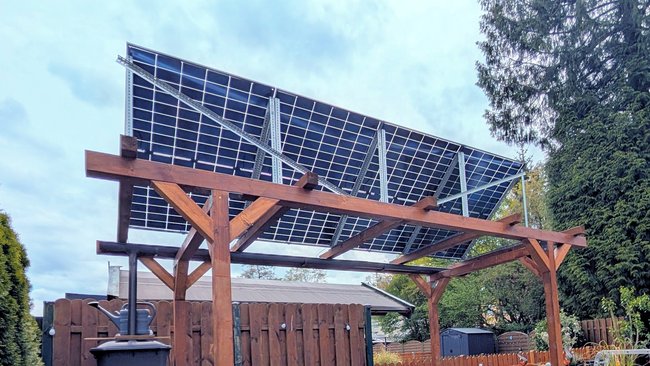 Aufnahme von 4 Solarmodulen, die auf einer Pergola in einem Garten aufgebaut sind. Aufnahme von 4 Solarmodulen, die auf einer Pergola in einem Garten aufgebaut sind.