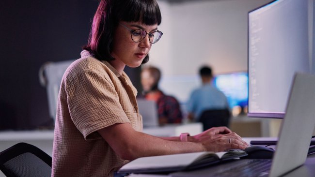 Eine junge Frau arbeitet am Laptop. In der Software-Entwicklung kommt zunehmend KI zum Einsatz. Eine junge Frau arbeitet am Laptop. In der Software-Entwicklung kommt zunehmend KI zum Einsatz.