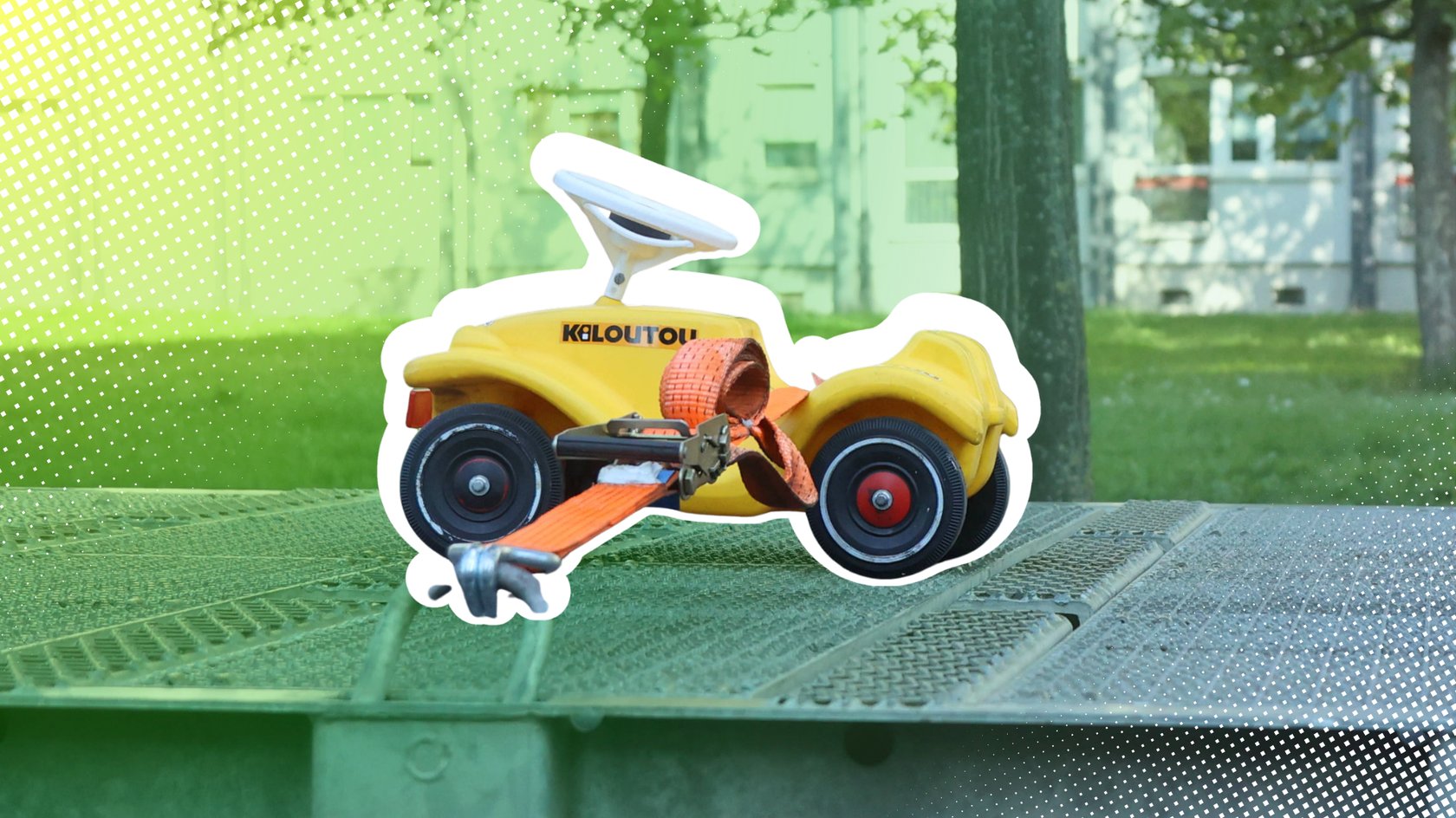 Gelbes Bobbycar auf einem Tieflader mit Gurten befestigt Gelbes Bobbycar auf einem Tieflader mit Gurten befestigt