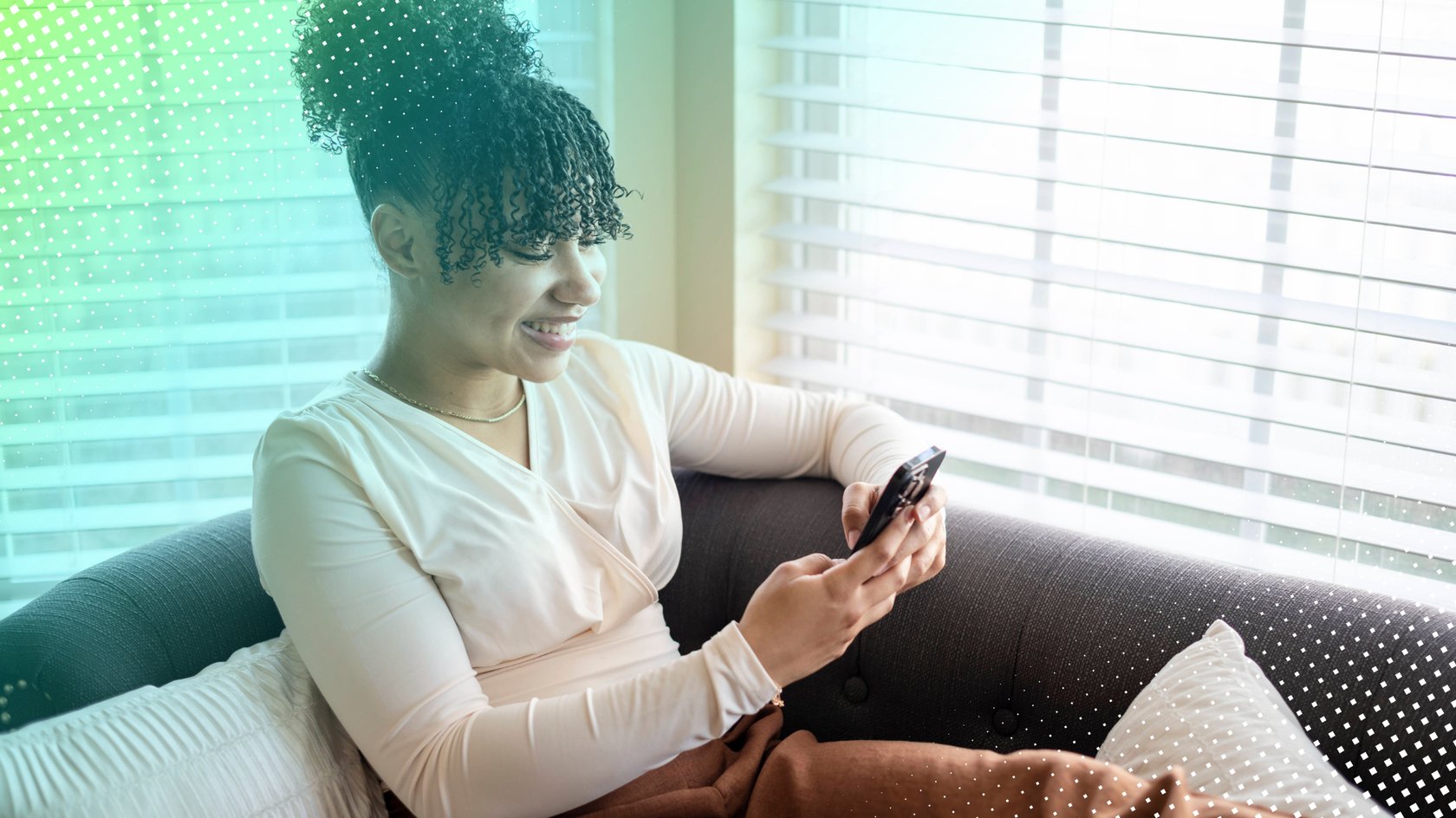 Frau sitzt auf Couch am Fenster und schaut auf Smartphone Frau sitzt auf Couch am Fenster und schaut auf Smartphone