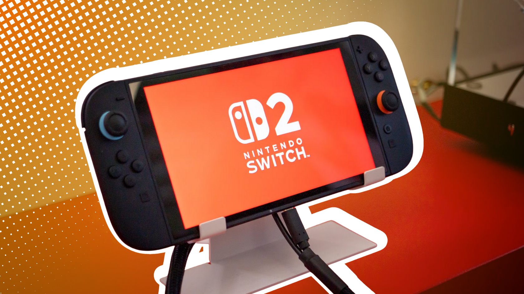 Nintendo Switch 2 auf einer Halterung mit Switch-2-Logo auf dem orangenen Display. Nintendo Switch 2 auf einer Halterung mit Switch-2-Logo auf dem orangenen Display.