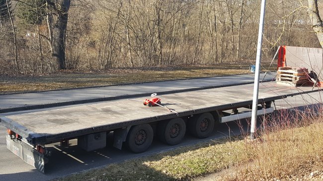 Kleines Bobbycar inmitten eines großen Tiefladers Kleines Bobbycar inmitten eines großen Tiefladers