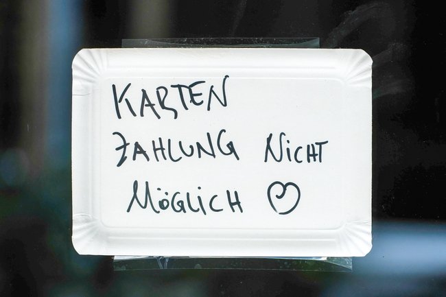 Pappschild mit der Aufschrift "Kartenzahlung nicht möglich" mit Klebeband an einer Glasscheibe. Pappschild mit der Aufschrift "Kartenzahlung nicht möglich" mit Klebeband an einer Glasscheibe.