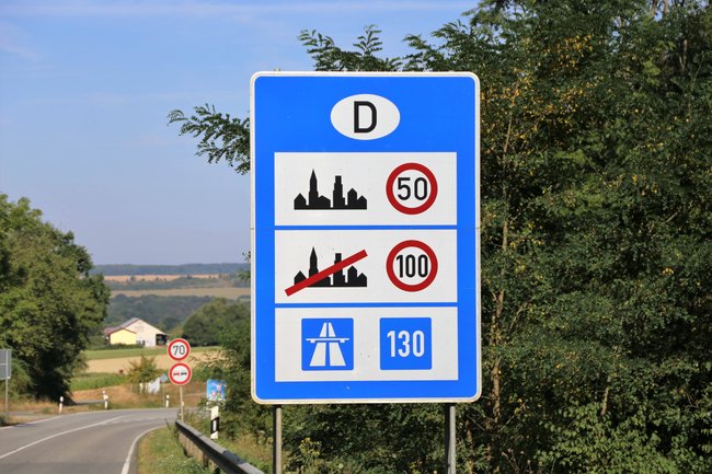 Blaues Schild mit Infos zu Höchstgeschwindigkeit in Städten und Außerhalb, als auch zur Richtgeschwindigkeit auf Autobahnen. Blaues Schild mit Infos zu Höchstgeschwindigkeit in Städten und Außerhalb, als auch zur Richtgeschwindigkeit auf Autobahnen.