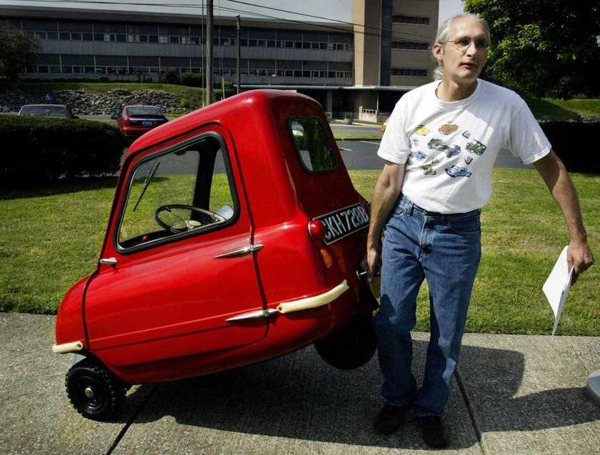 Mann zieht rotes, kleines Auto hinter sich her. Mann zieht rotes, kleines Auto hinter sich her.