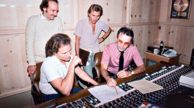 Der italienische Komponist und Produzent Giorgio Moroder (in Hemd und Krawatte) mit seinem Produktionsteam im November 1982 in Moroders Heimstudio in Los Angeles, Kalifornien. Der italienische Komponist und Produzent Giorgio Moroder (in Hemd und Krawatte) mit seinem Produktionsteam im November 1982 in Moroders Heimstudio in Los Angeles, Kalifornien.