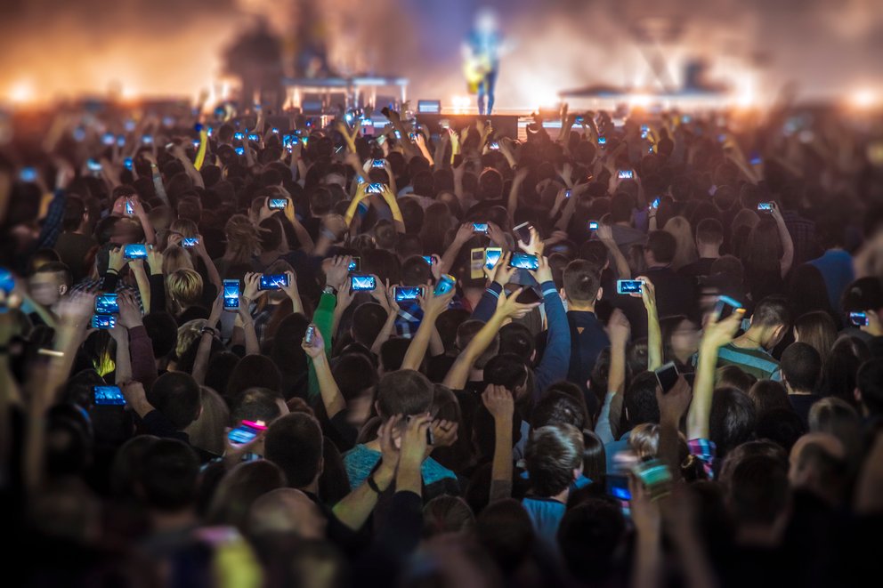 people at the concert with the phones shoot the show