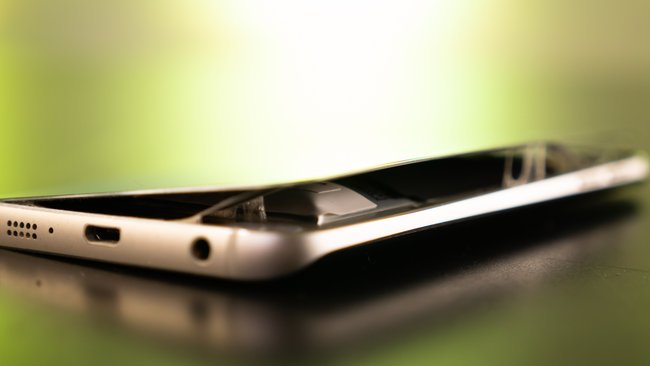 Eine Smartphone mit kaputter Rückseite liegt auf einem Tisch.