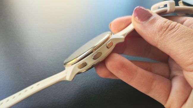 Die weiße Smartwatch Venu 2 Plus ist von der Seite mit drei Tasten zu sehen. Die wird von einer Hand gehalten.