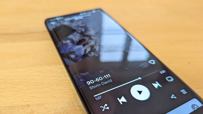 Das Smartphone Honor 70 liegt mit geöffnetem Display auf einem Tisch, auf Spotify läuft "9-60-111" von Shirin David.