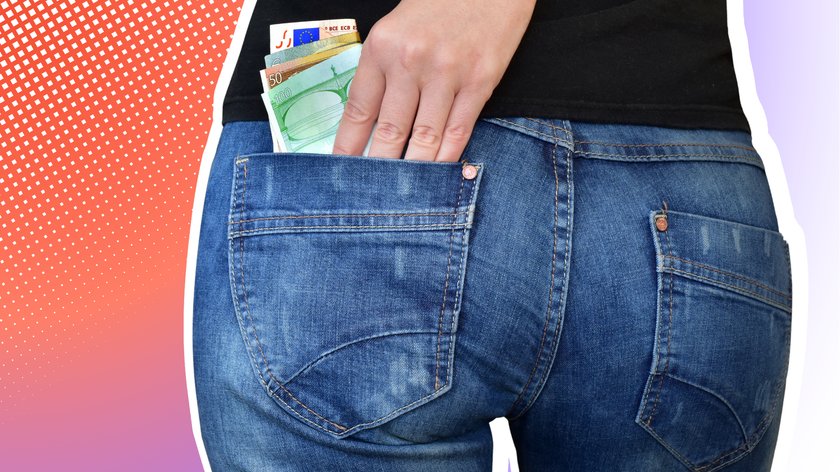 Nahaufnahme einer Person, die Geldscheine in die hintere Tasche einer blauen Jeans steckt. Die Person trägt ein schwarzes Oberteil, und es sind Euro-Scheine sichtbar, darunter 50- und 100-Euro-Noten. Der Hintergrund ist grafisch gestaltet mit roten und violetten Farbverläufen sowie einem Muster aus weißen Punkten.