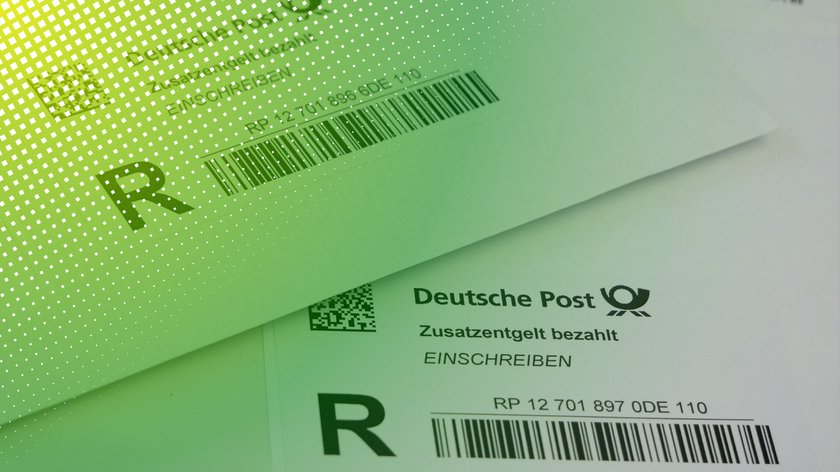 Nahaufnahme von zwei Einschreiben-Labels der Deutschen Post auf Briefumschlägen. Die Etiketten enthalten das Logo der Deutschen Post, den Vermerk „Zusatzentgelt bezahlt“, das Wort „EINSCHREIBEN“ in Fettdruck.