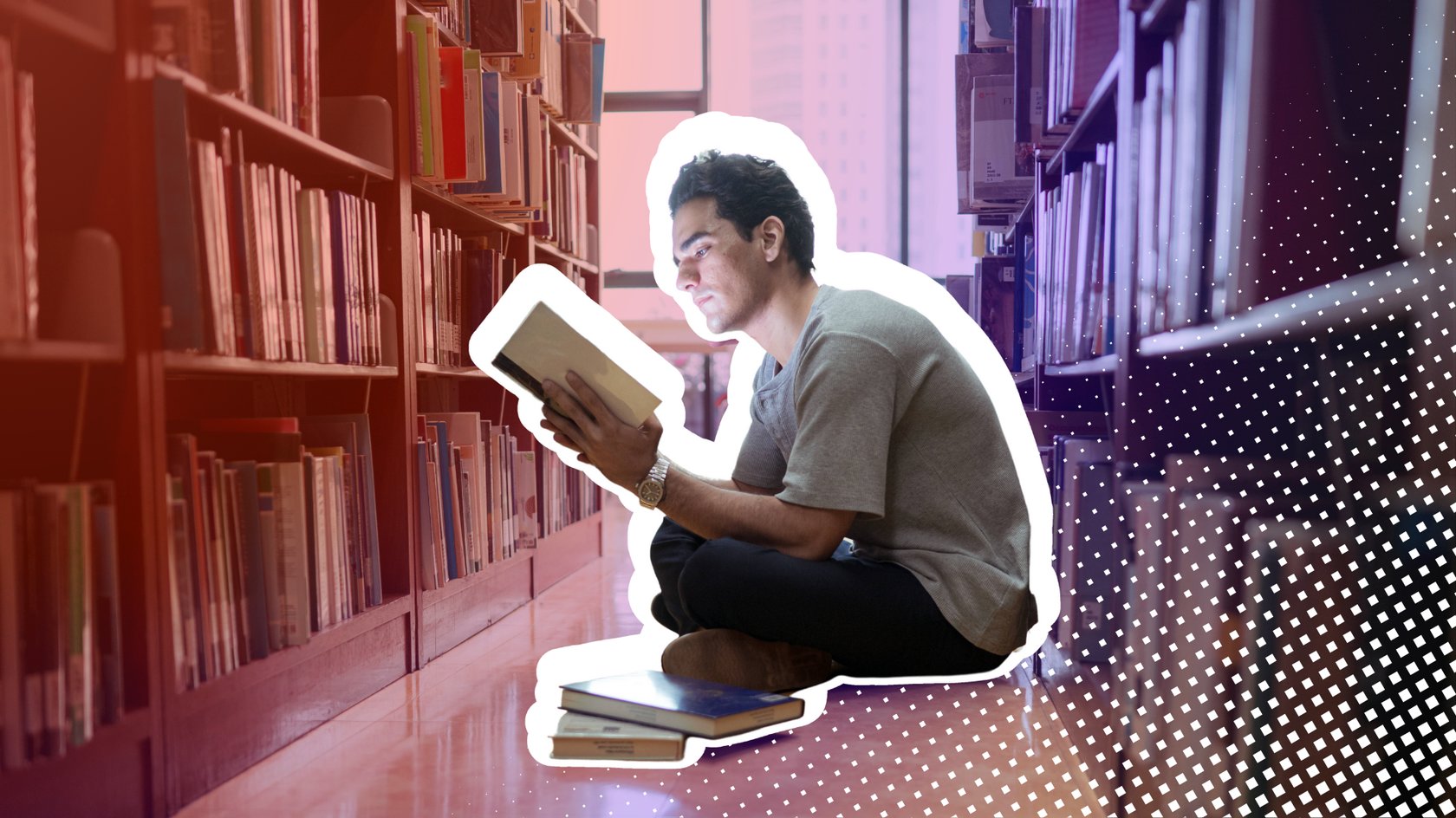 Ein junger Mann sitzt in der Bibliothek und liest konzentriert ein Buch.