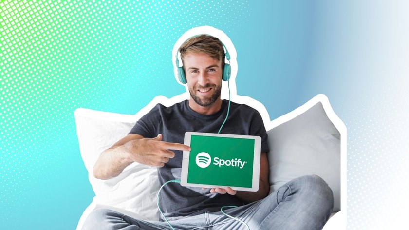 Junger Mann hält Tablet mit Spotify App 