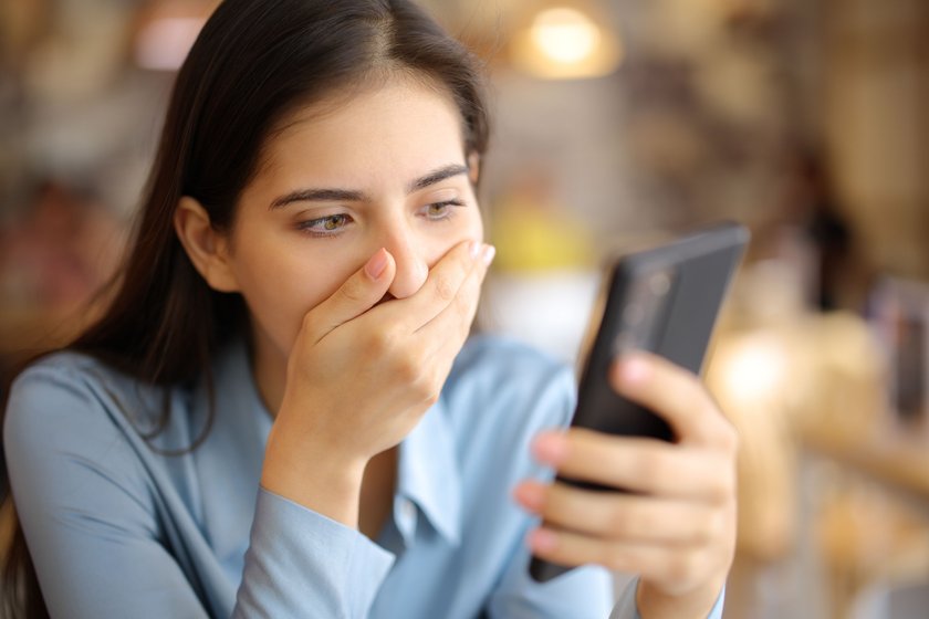 Shocked woman watching videos on phone in a bar