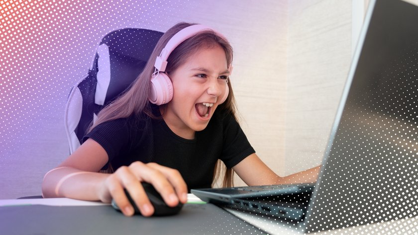 Mädchen mit Headset sitzt zur Gaming-Laptop und lacht.