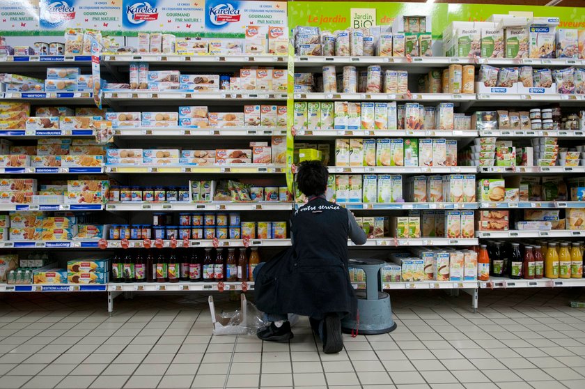 Discounter-Mitarbeiter räumt Produkte in Regal um