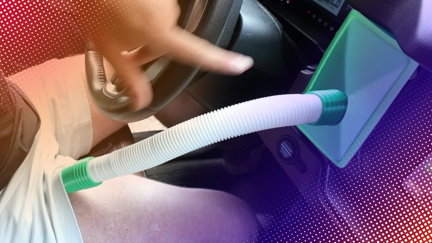 Innenansicht eines Autos mit einer Person, die auf eine grüne Vorrichtung mit einem weißen, gerippten Schlauch zeigt, der zu ihrem Bein führt.