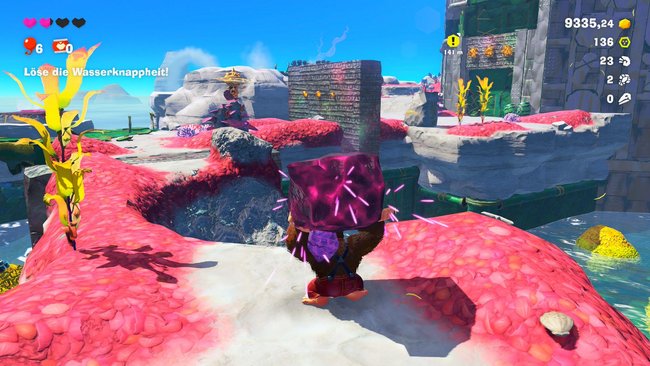 Donkey Kong mit einem Felsbrocken auf den Schultern in einem Level von DK: Bananza.