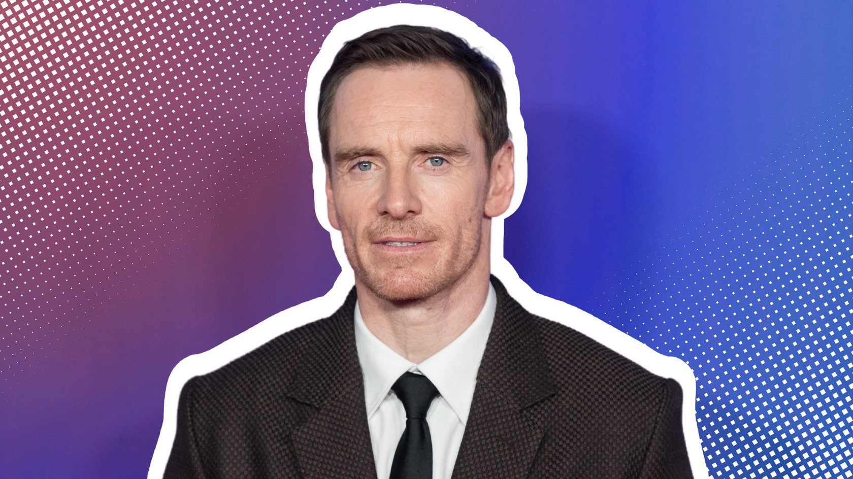 Michael Fassbender im dunklen Anzug vor einer blauen Wand.
