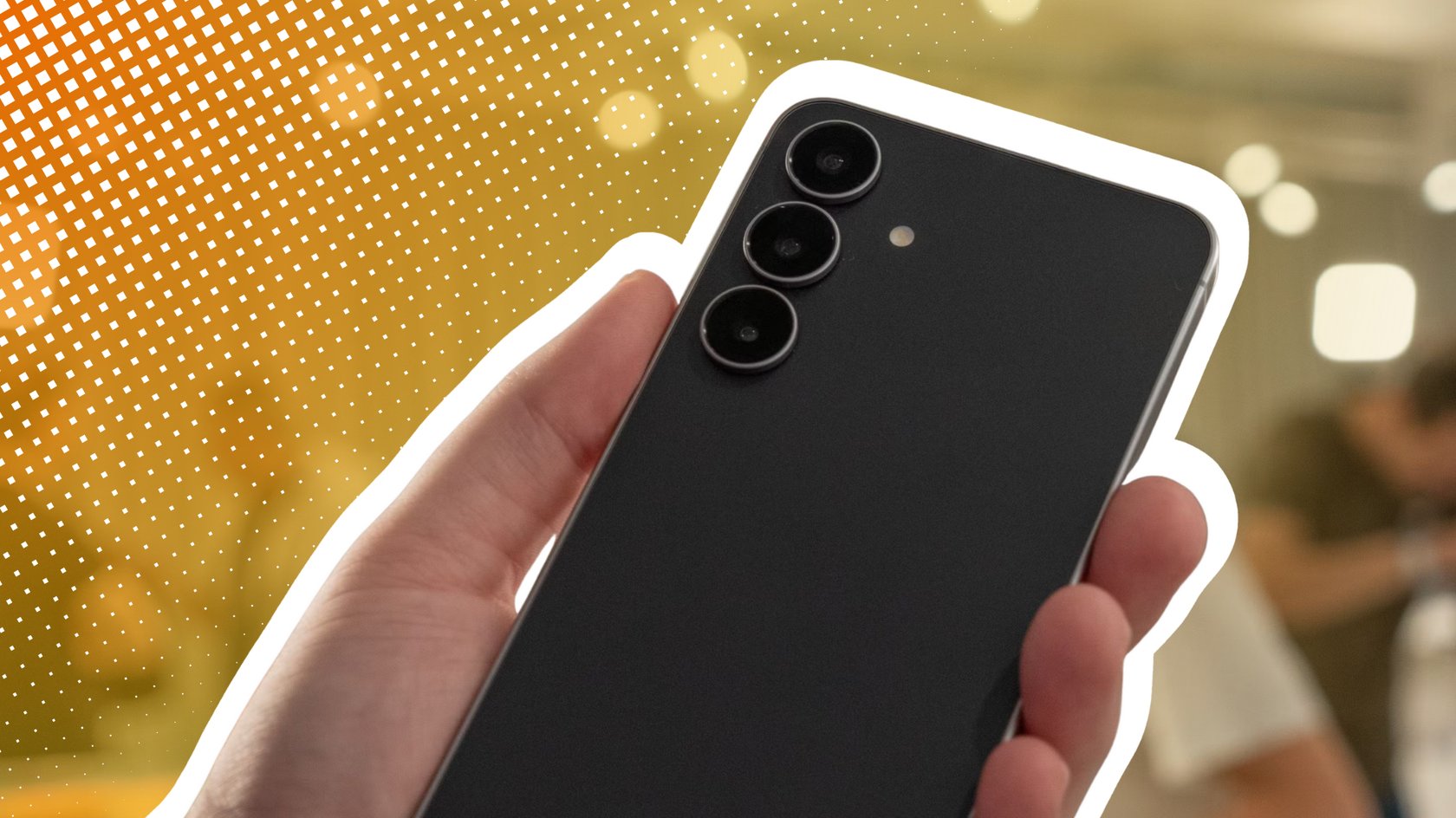 Samsung Galaxy S25 FE in einer Hand gehalten vor einem gelben Hintergrund.