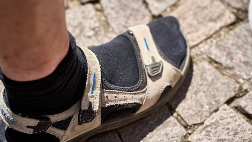 Malcesine, Lake Garda, Italy - 20 July 2024: Symbolic image of a typical German man wearing sandals with socks on vacation *** Symbolbild eines typisch deutschen Mannes, der im Urlaub Sandalen mit Socken trägt