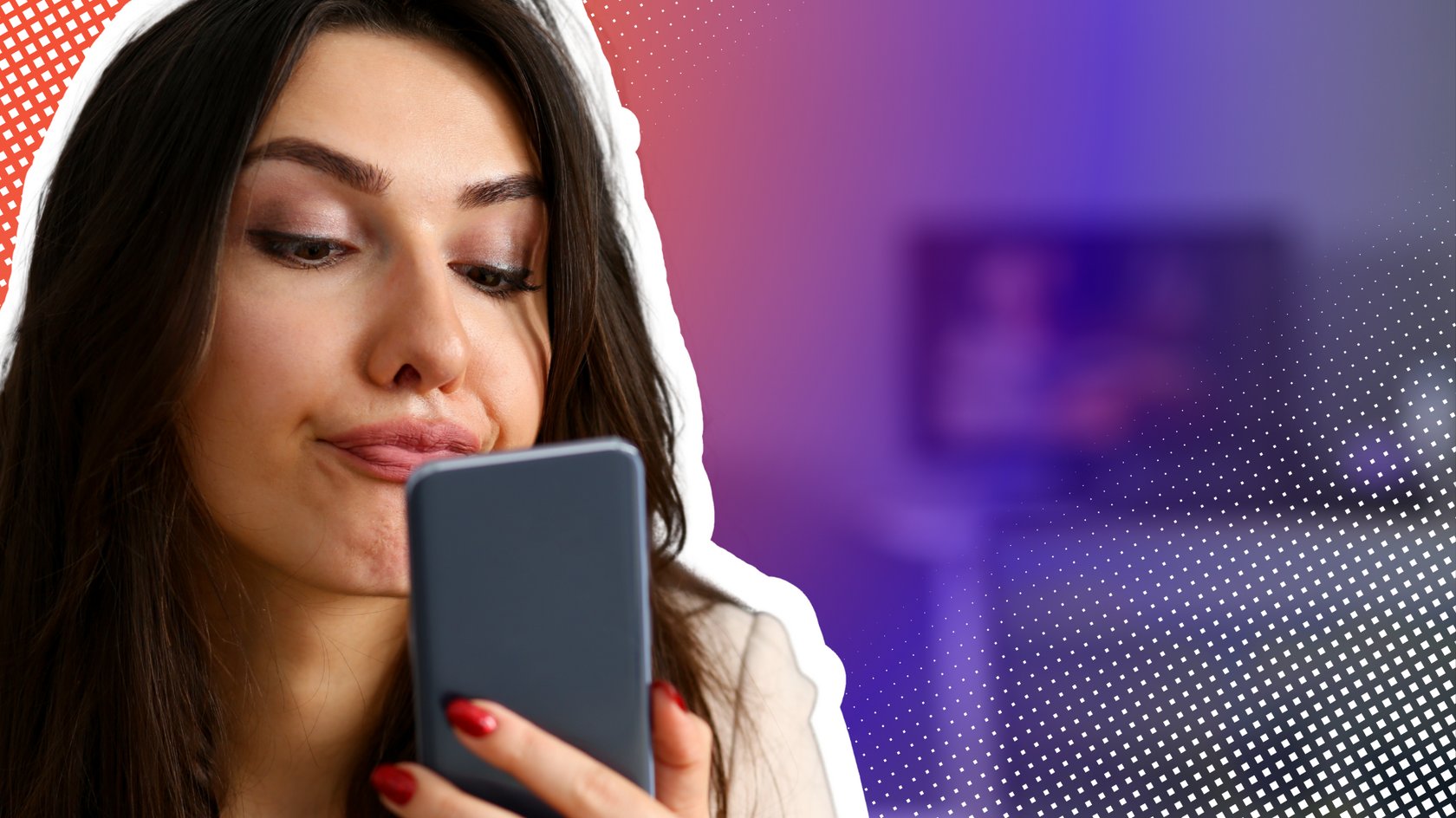 Eine junge Frau mit langen braunen Haaren und rotem Nagellack blickt nach unten auf ihr Smartphone und spitzt die Lippen. Im Hintergrund sind ein Laptop und ein Monitor zu sehen.