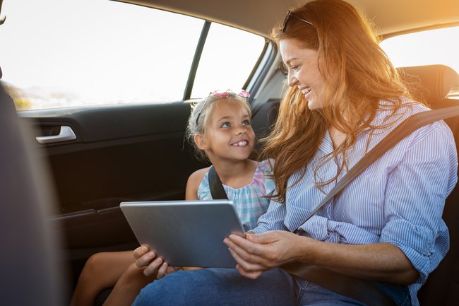 Mutter und Tochter im Auto mit einem Tablet.