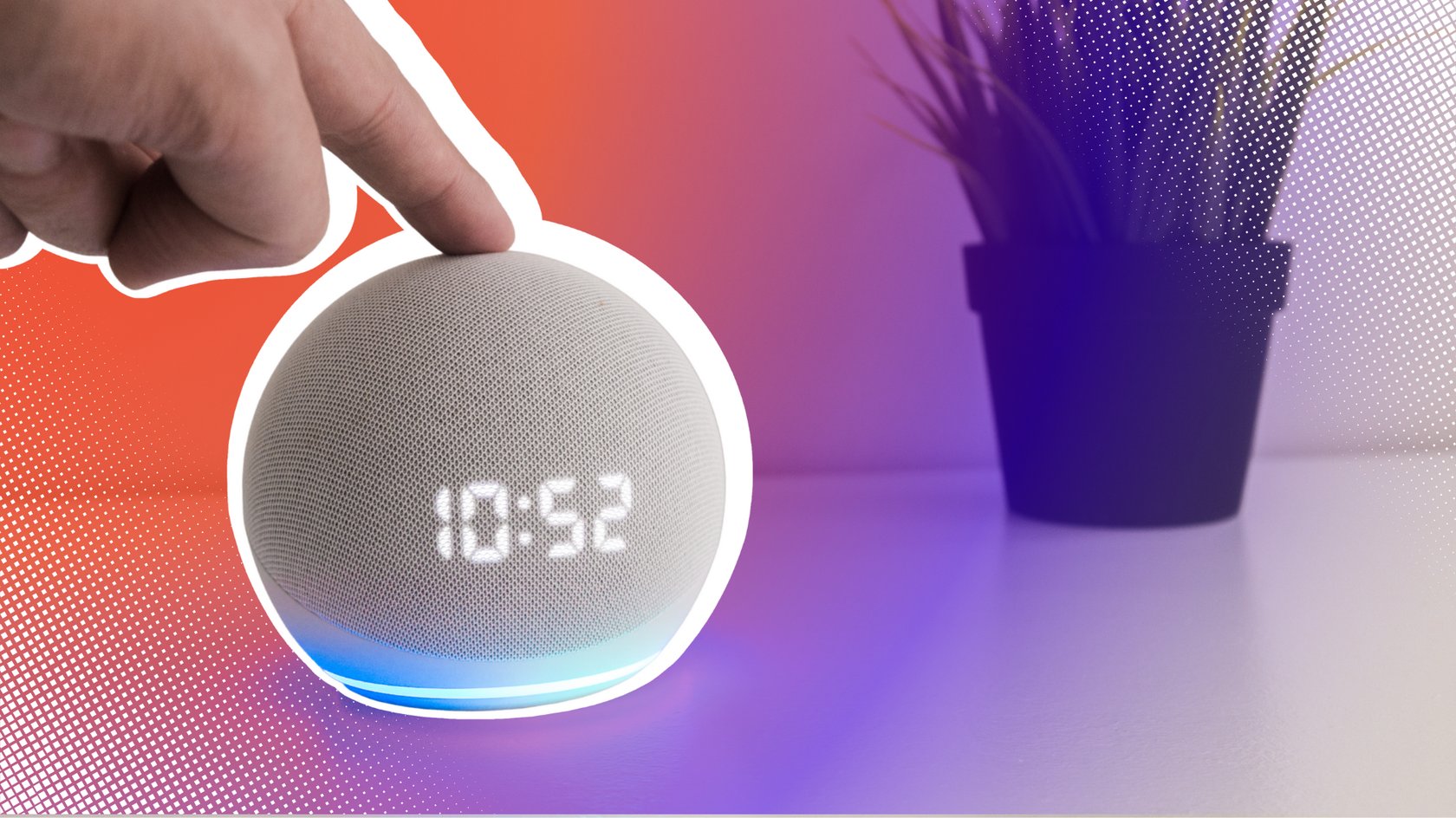 Nahaufnahme einer Hand, die einen kugelförmigen, hellgrauen Smart Speaker mit digitaler Zeitanzeige (10:52) und blauem Licht berührt; im Hintergrund eine kleine Topfpflanze.