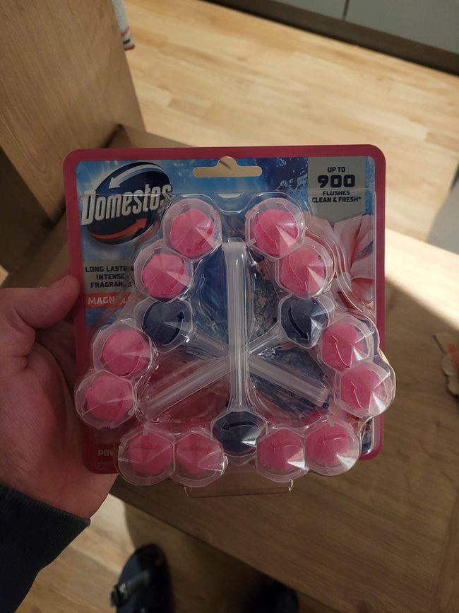 Domestos-Klostein in Rosa in der Hand gehalten.