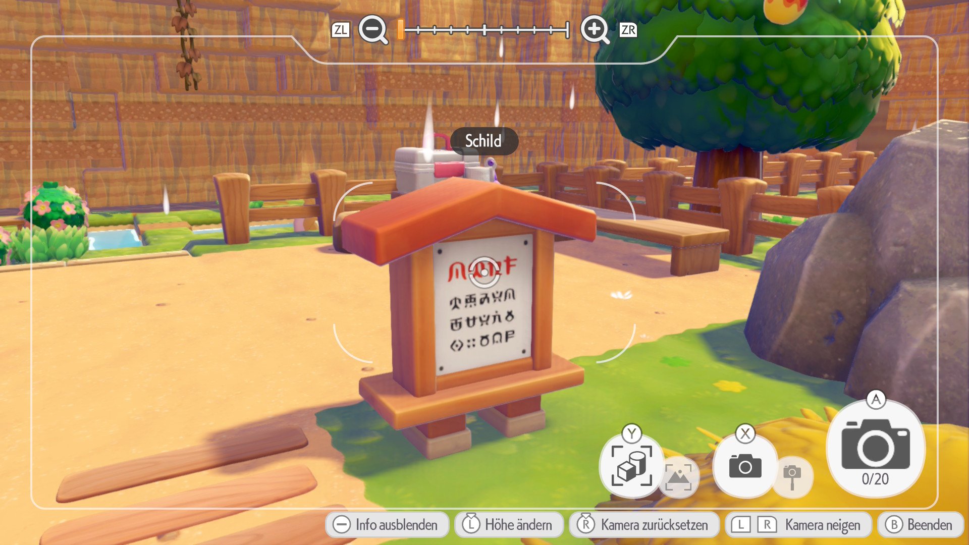 A sign with unknown symbols stands on a wooden stand. A wooden fence, a tree and a rocky structure can be seen in the background.