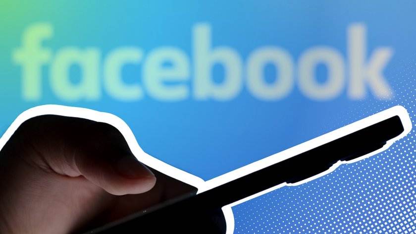 Eine Hand hält ein Smartphone vor einem unscharfen Hintergrund mit dem Facebook-Logo. Der Hintergrund ist in Blautönen gehalten und der Schriftzug "facebook" ist in weißer Farbe.