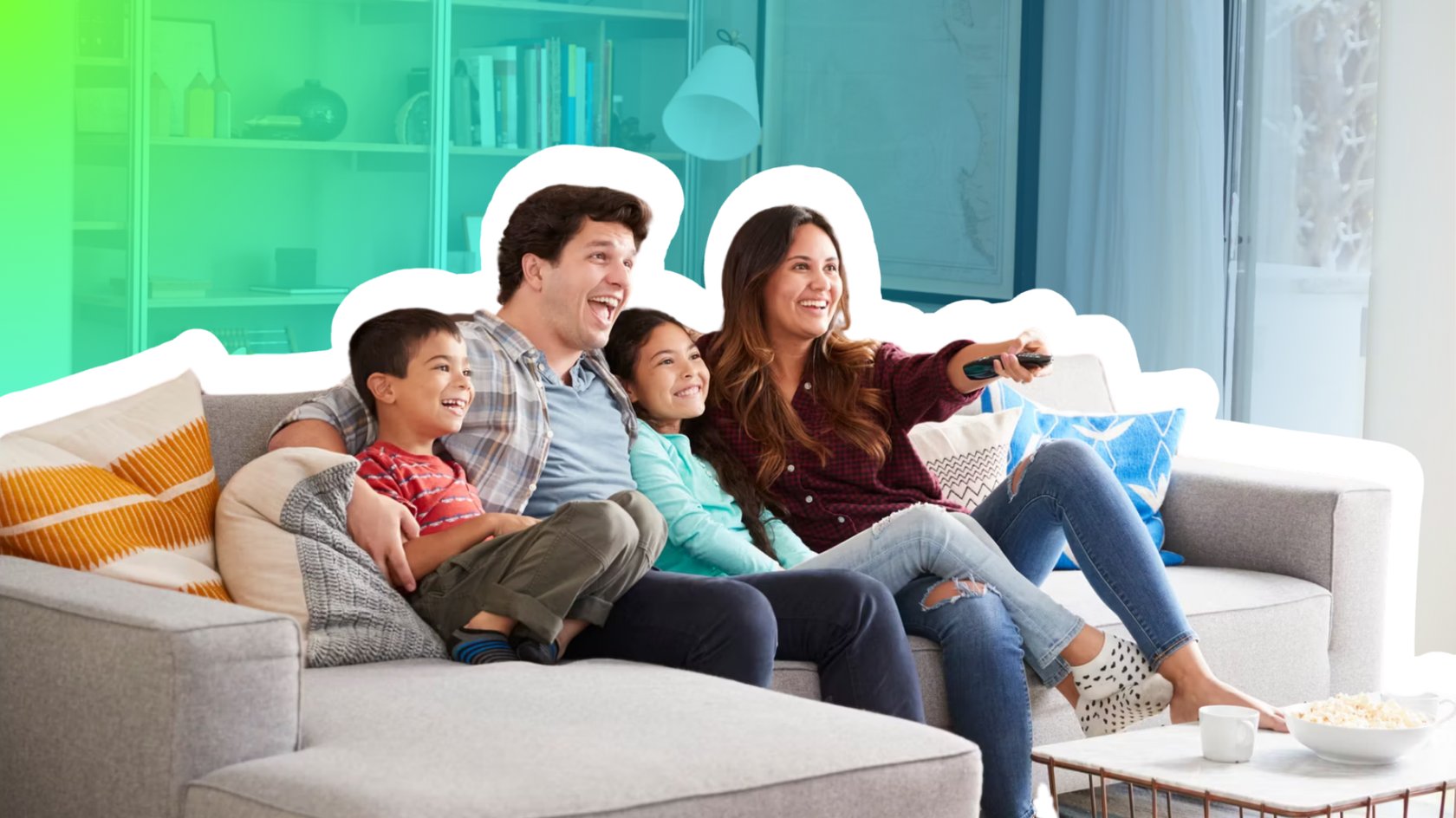 Glückliche Familie sitzt lachend auf dem Soga und schaut zusammen fernsehen. Von links: Sohn, Vater, Tochter, Mutter mit Fernbedienung in der Hand.