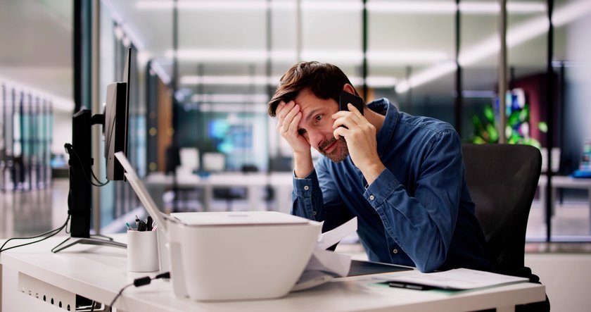 Mann im Büro ist genervt von dem defekten Drucker