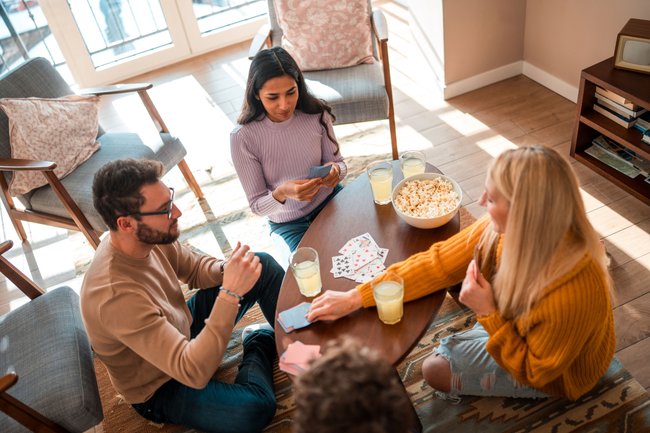 Drei Personen spielen ein Kartenspiel im Wohnzimmer