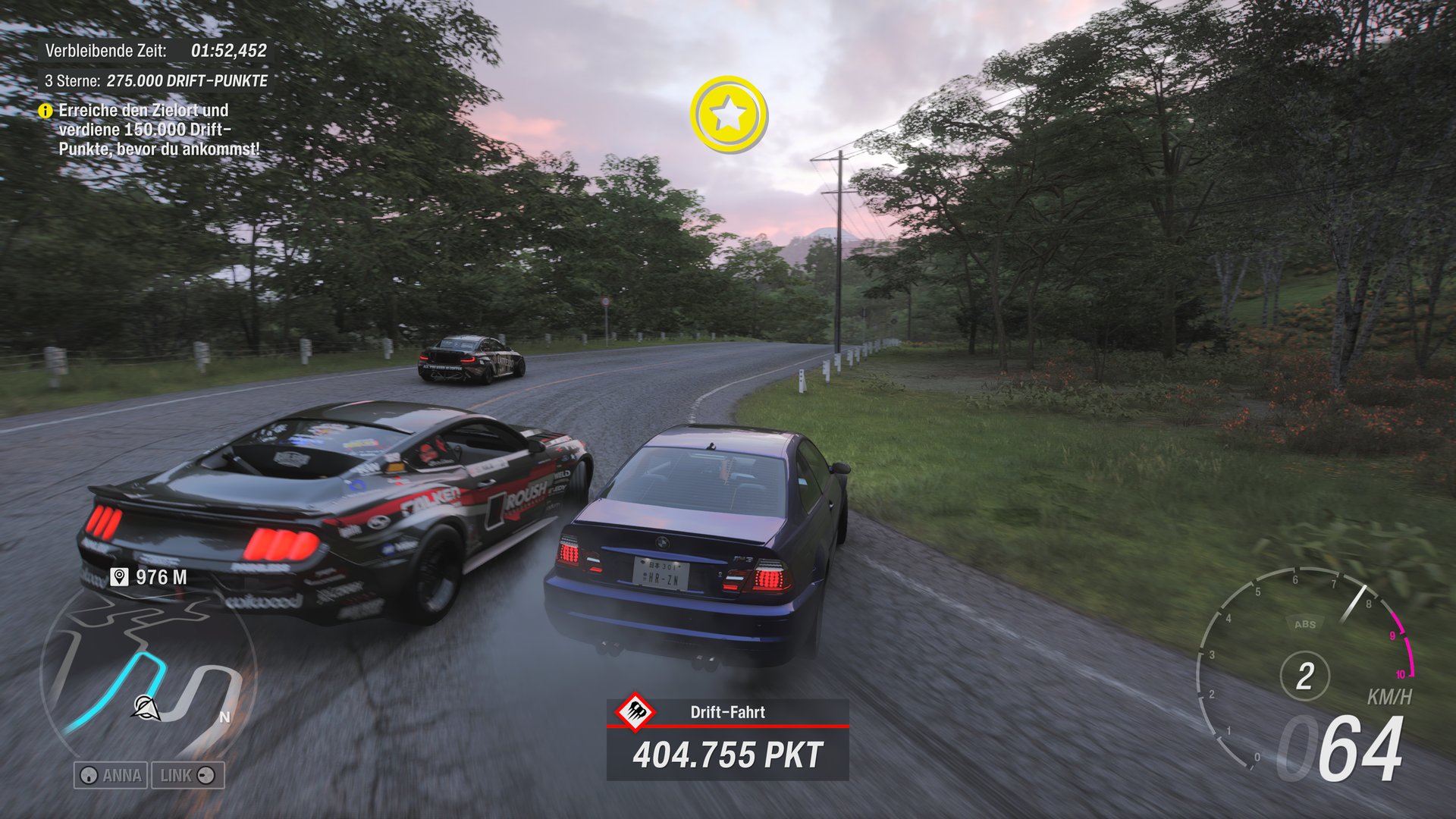 Two cars drive on a winding, wet road through a wooded landscape. The car in front is a dark Ford Mustang with distinctive stickers. The car in the back is a dark blue BMW M3. A star symbol appears in the sky and information such as remaining time, drift points and speed are displayed on the screen.