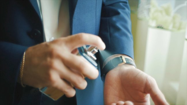 Close-up of handsome business man or groom using perfume. Clip.