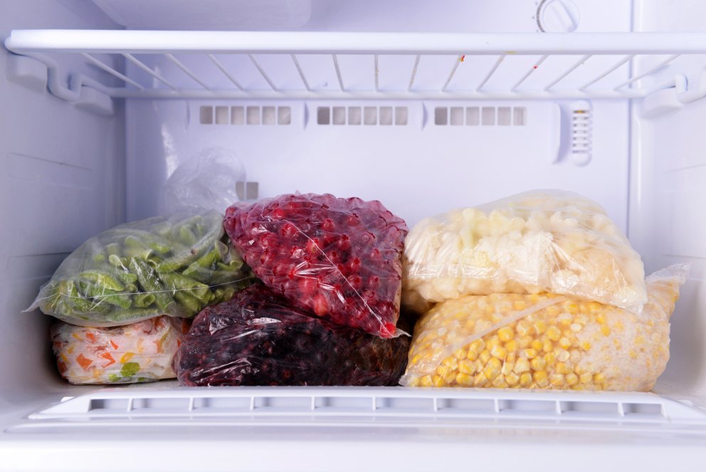 Frozen berries and vegetables in bags in freezer close up