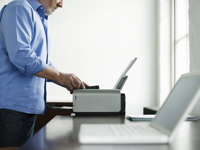 Side view midsection of a mature man using printer