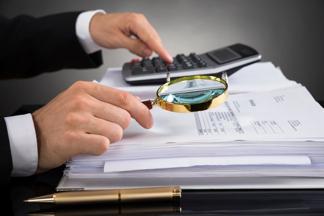 Businessperson Checking Invoice With Magnifying Glass