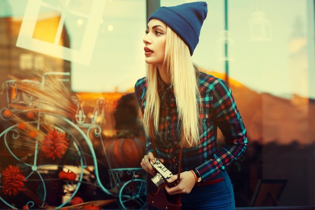 Portrait of beautiful young playful hipster woman with old retro camera. Model looking aside. City lifestyle. Toned
