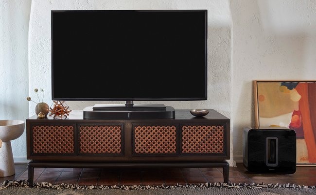 Die PLAYBASE ist unter dem TV platziert und dient zugleich Stellfläche, rechts im Bild ist der optionale SUB zu sehen (Quelle: SONOS)