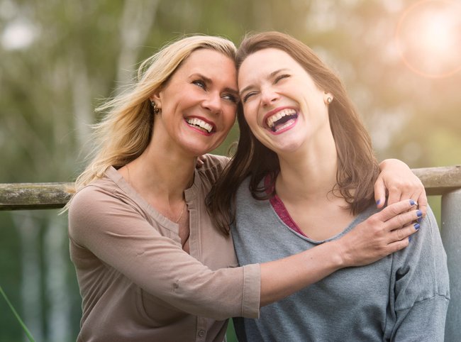 two woman hugging each other outdoors and laughing
