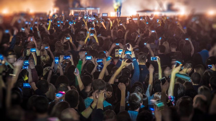 people at the concert with the phones shoot the show