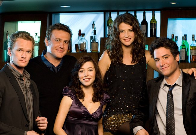 Die Darstellerinnen und Darsteller der Sitcom "How I Met Your Mother" stehen nebeneinander vor einer Bar.