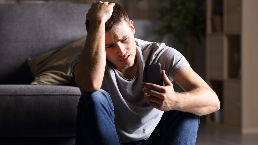 Sad man checking mobile phone