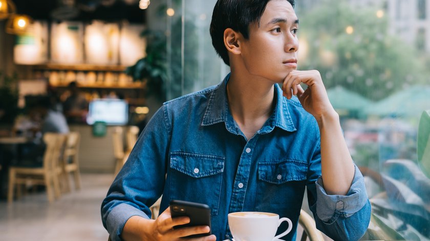 Mann in einem Café mit Handy