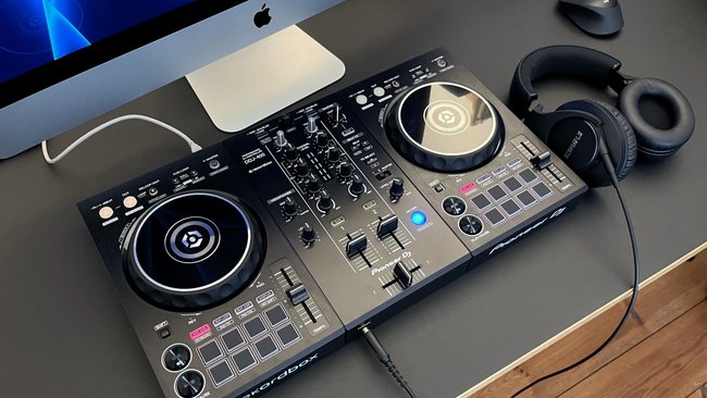 Ein DJ-Controller, Modell Pioneer DJ DDJ-400, auf einem Schreibtisch. Rechts daneben liegt ein Kopfhörer von Shure.