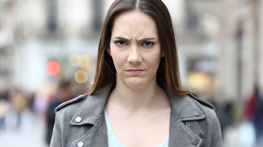 Angry woman looking at camera on city street