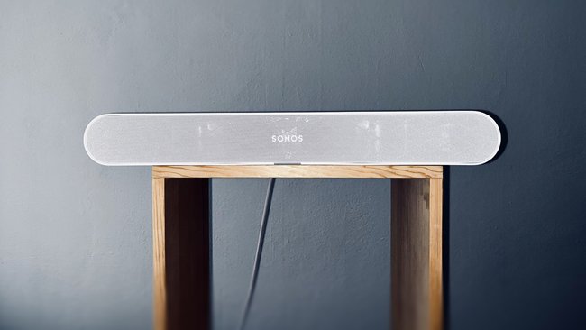 Auf einem minimalistischen Hocker aus Holz steht eine Soundbar, die Sonos Ray.